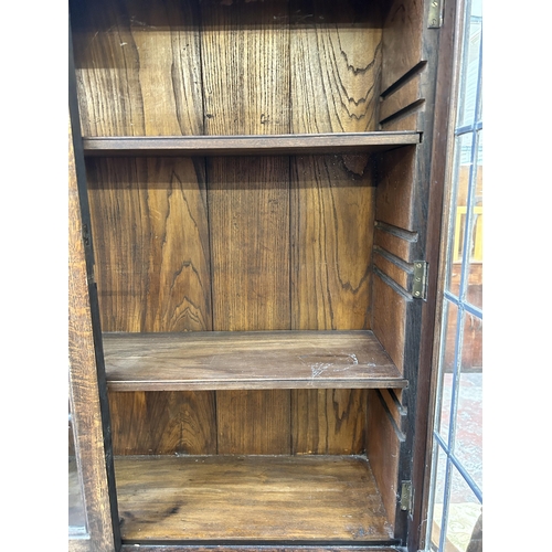 169 - An early 20th century carved oak bureau bookcase with two upper leaded and stained glass doors - app... 