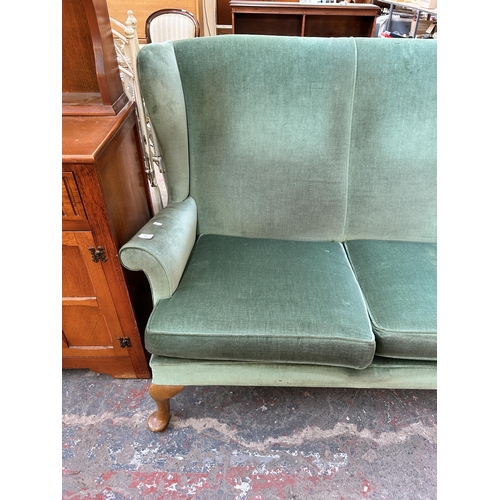 173 - A Parker Knoll green fabric upholstered two seater wingback sofa