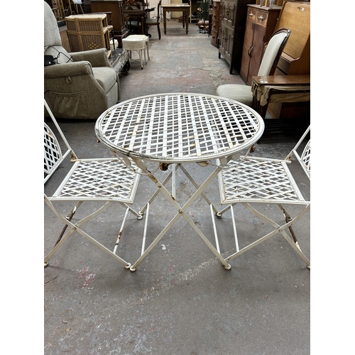 180 - A white painted metal circular folding patio table and two chairs - approx. 75cm high x 70cm diamete... 