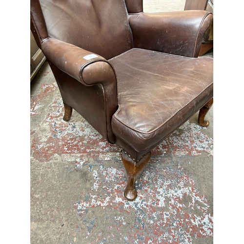 59 - A brown leather wingback armchair on cabriole supports