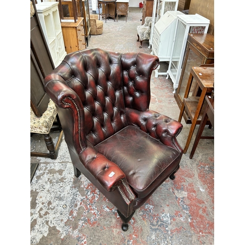 99 - An ox blood leather Chesterfield wingback armchair on cabriole supports