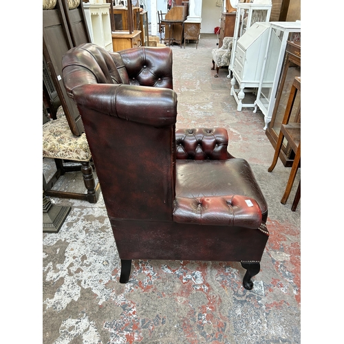 99 - An ox blood leather Chesterfield wingback armchair on cabriole supports