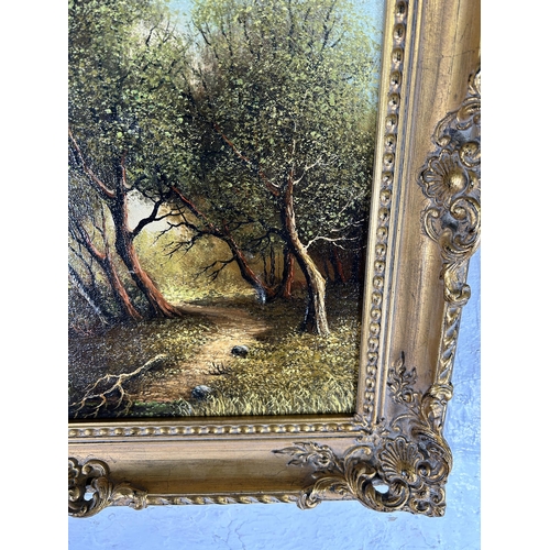 236 - A gilt framed H. Sanders oil on canvas of a landscape scene - approx. 55cm high x 65cm wide