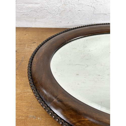 273 - An Edwardian mahogany framed bevelled edge oval wall mirror with beaded decoration - approx. 52cm hi... 