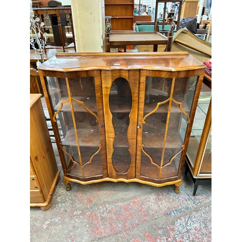 106 - An Art Deco style walnut display cabinet with two glazed doors and cabriole supports