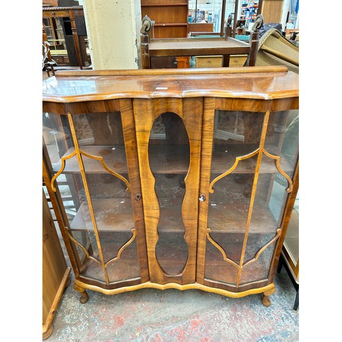 106 - An Art Deco style walnut display cabinet with two glazed doors and cabriole supports