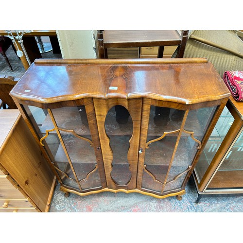 106 - An Art Deco style walnut display cabinet with two glazed doors and cabriole supports