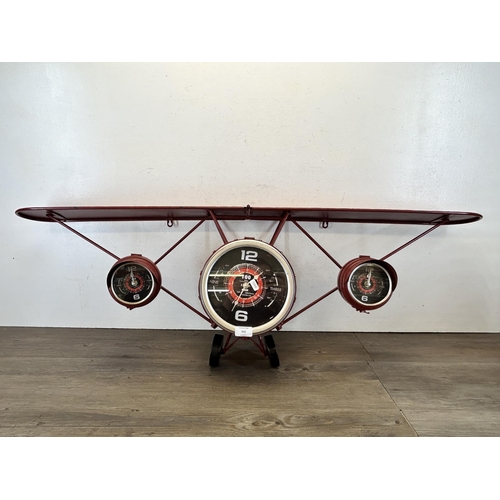 602 - A red metal wall clock in the form of a bi-plane