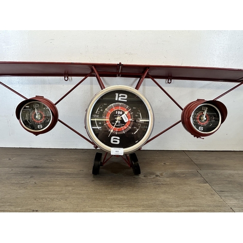 602 - A red metal wall clock in the form of a bi-plane