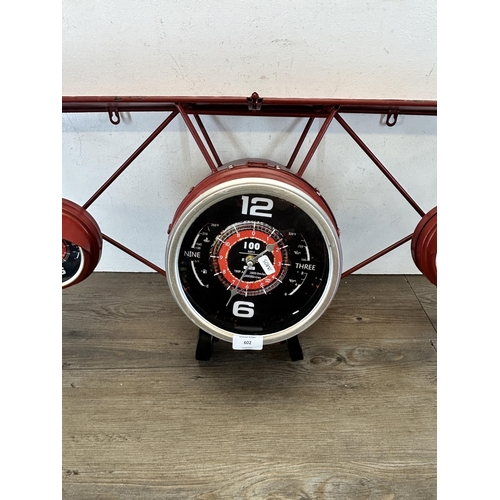 602 - A red metal wall clock in the form of a bi-plane