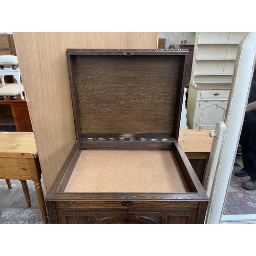 103 - An early 20th century carved oak two door gramophone cabinet - approx. 104cm high x 72cm wide x 59cm... 