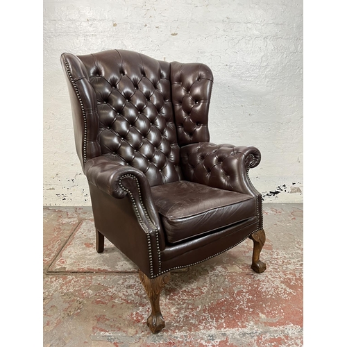 13 - A brown leather Chesterfield wingback armchair on ball and claw supports