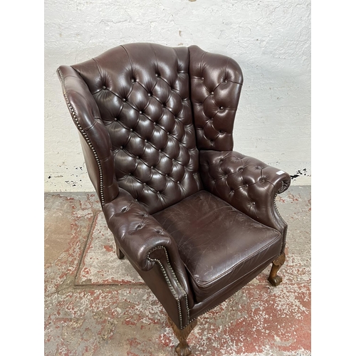 13 - A brown leather Chesterfield wingback armchair on ball and claw supports