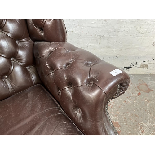 13 - A brown leather Chesterfield wingback armchair on ball and claw supports