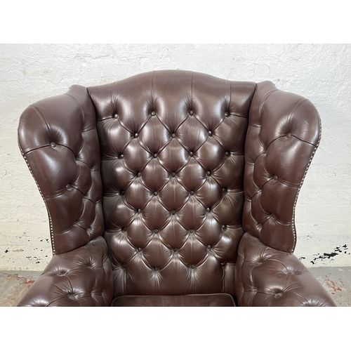 13 - A brown leather Chesterfield wingback armchair on ball and claw supports