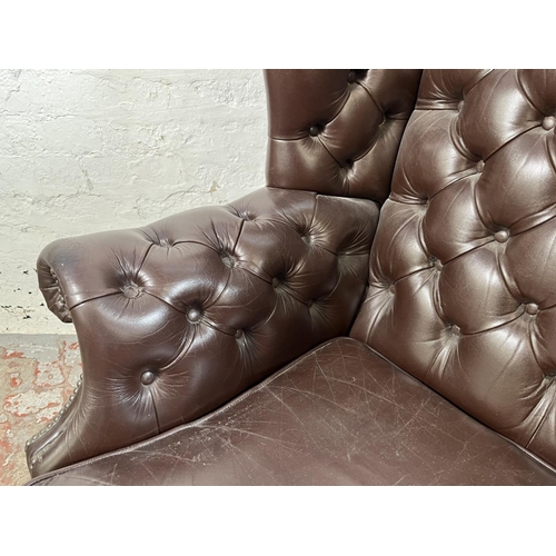 13 - A brown leather Chesterfield wingback armchair on ball and claw supports