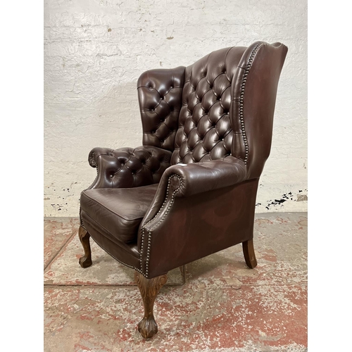 13 - A brown leather Chesterfield wingback armchair on ball and claw supports