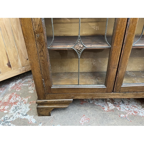 33 - An early 20th century oak and lead glazed two door bookcase - approx. 128cm high x 92cm wide x 26cm ... 