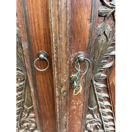 49 - An Indonesian carved teak two door cabinet - approx. 166cm high x 114cm wide x 49cm deep