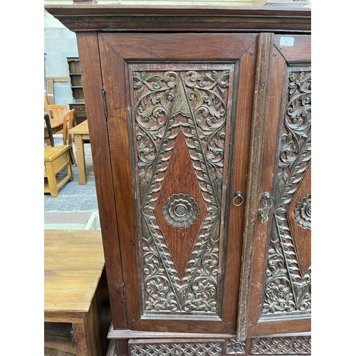 49 - An Indonesian carved teak two door cabinet - approx. 166cm high x 114cm wide x 49cm deep