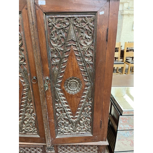 49 - An Indonesian carved teak two door cabinet - approx. 166cm high x 114cm wide x 49cm deep