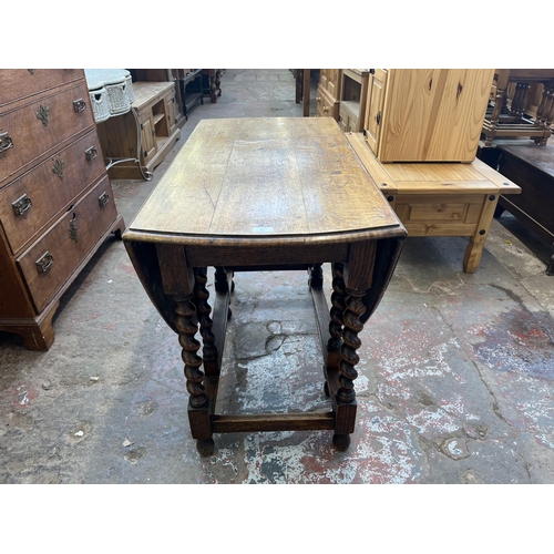 62 - An early 20th century oak drop leaf gate leg dining table on barley twist supports - approx. 73cm hi... 