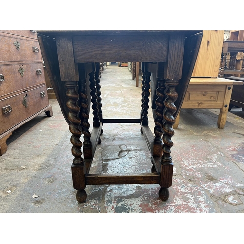 62 - An early 20th century oak drop leaf gate leg dining table on barley twist supports - approx. 73cm hi... 