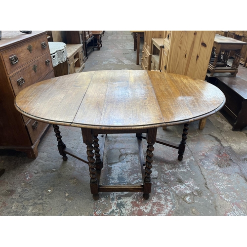 62 - An early 20th century oak drop leaf gate leg dining table on barley twist supports - approx. 73cm hi... 