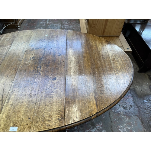 62 - An early 20th century oak drop leaf gate leg dining table on barley twist supports - approx. 73cm hi... 