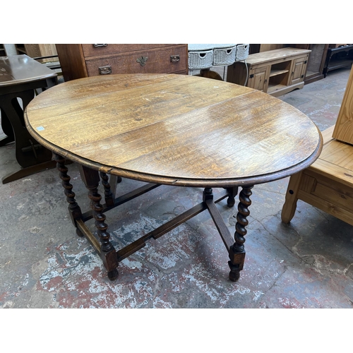 62 - An early 20th century oak drop leaf gate leg dining table on barley twist supports - approx. 73cm hi... 