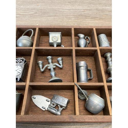 519 - A rectangular model display case containing a collection of pewter ornaments to include candelabras,... 