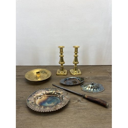 296 - A collection of metalware to include two pairs of brass candlesticks, brass chamber stick, brass lad... 