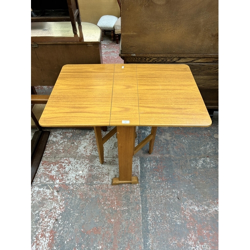 129 - A mid 20th century beech and teak effect drop leaf gate leg kitchen table - approx. 77cm high x 60cm... 