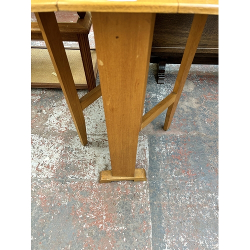 129 - A mid 20th century beech and teak effect drop leaf gate leg kitchen table - approx. 77cm high x 60cm... 