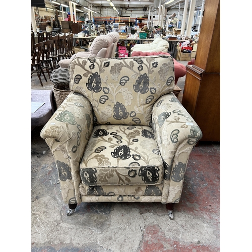 146 - A Victorian style floral fabric upholstered armchair on turned mahogany supports and castors