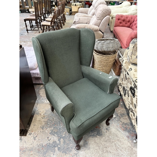 147 - A green fabric upholstered wingback armchair on cabriole supports