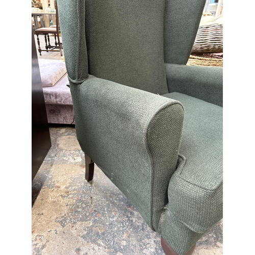 147 - A green fabric upholstered wingback armchair on cabriole supports