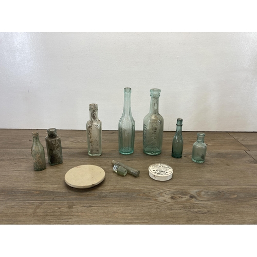 252 - A collection of antique glass bottles together with a ceramic pot lid