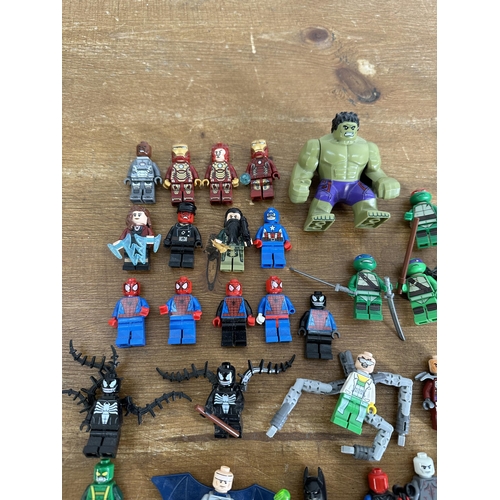 337 - A collection of film and superhero related Lego figurines to include Ironman, Batman, Indiana Jones,... 