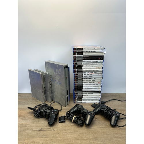 692 - Three silver Sony PlayStation 2 consoles, controllers and games to include The Getaway, The Sims 2 a... 