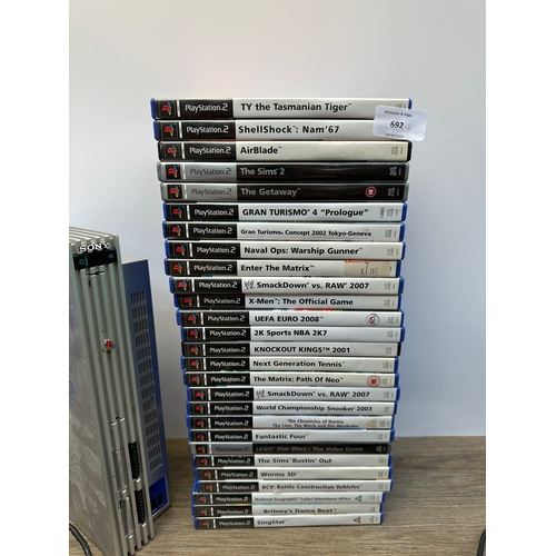 692 - Three silver Sony PlayStation 2 consoles, controllers and games to include The Getaway, The Sims 2 a... 