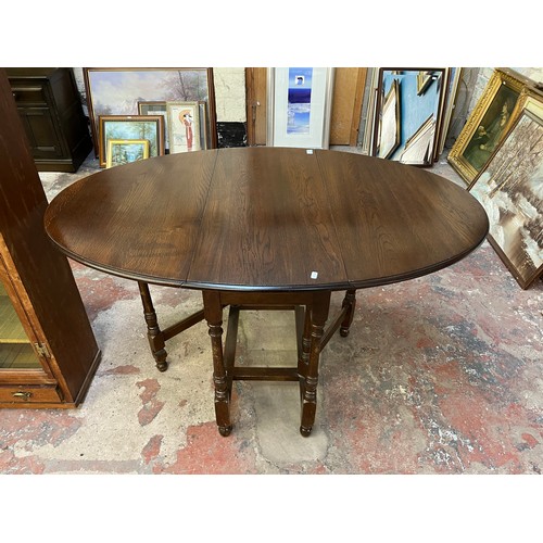 22 - A mid 20th century oak drop leaf gate leg oval dining table - approx. 75cm high x 90cm wide x 146cm ... 