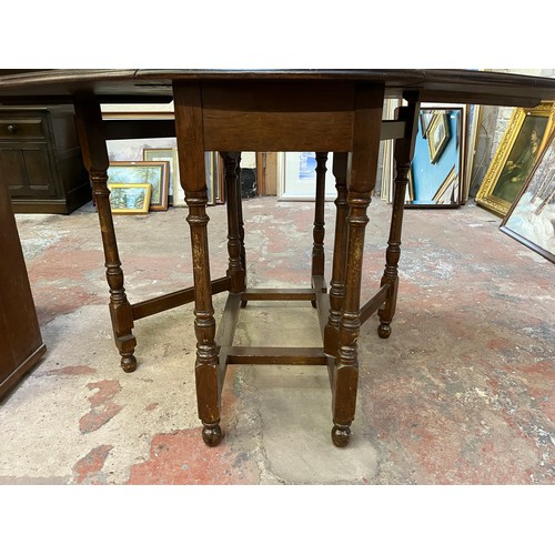 22 - A mid 20th century oak drop leaf gate leg oval dining table - approx. 75cm high x 90cm wide x 146cm ... 