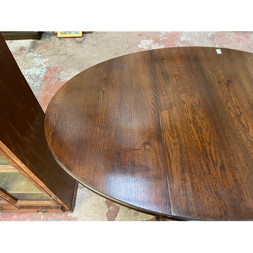 22 - A mid 20th century oak drop leaf gate leg oval dining table - approx. 75cm high x 90cm wide x 146cm ... 