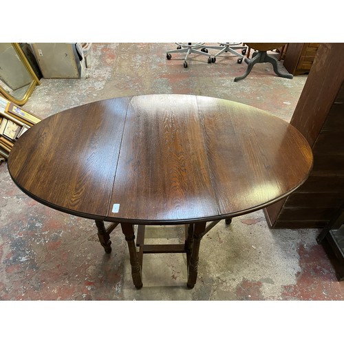 22 - A mid 20th century oak drop leaf gate leg oval dining table - approx. 75cm high x 90cm wide x 146cm ... 