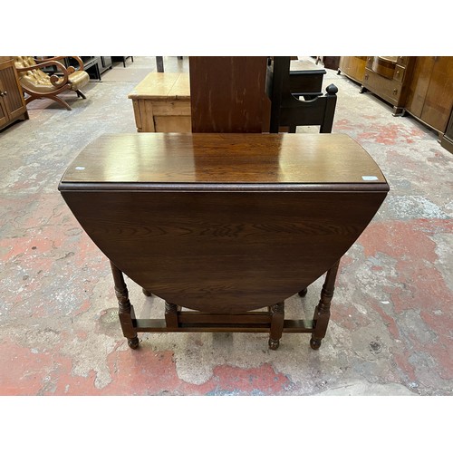 22 - A mid 20th century oak drop leaf gate leg oval dining table - approx. 75cm high x 90cm wide x 146cm ... 