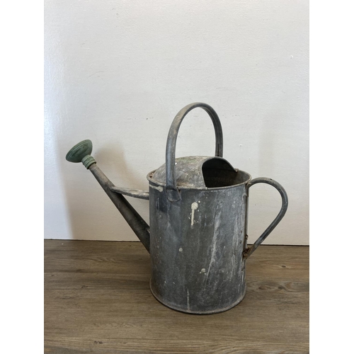 327A - Three pieces of metalware, two mid 20th century galvanised watering cans and one Shell Motor Spirit ... 