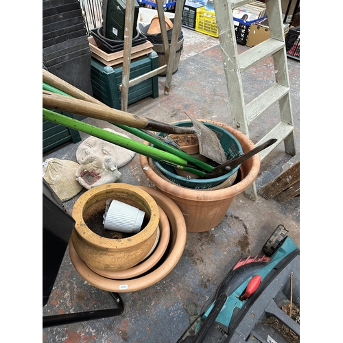 869 - A collection of garden items to include compost mixer, terracotta planters, spade etc.