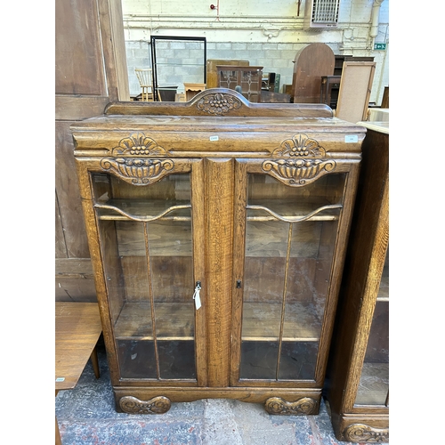 106 - An Art Deco style carved oak and glazed two door bookcase - approx. 131cm high x 90cm wide x 29cm de... 