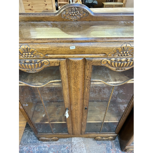 106 - An Art Deco style carved oak and glazed two door bookcase - approx. 131cm high x 90cm wide x 29cm de... 